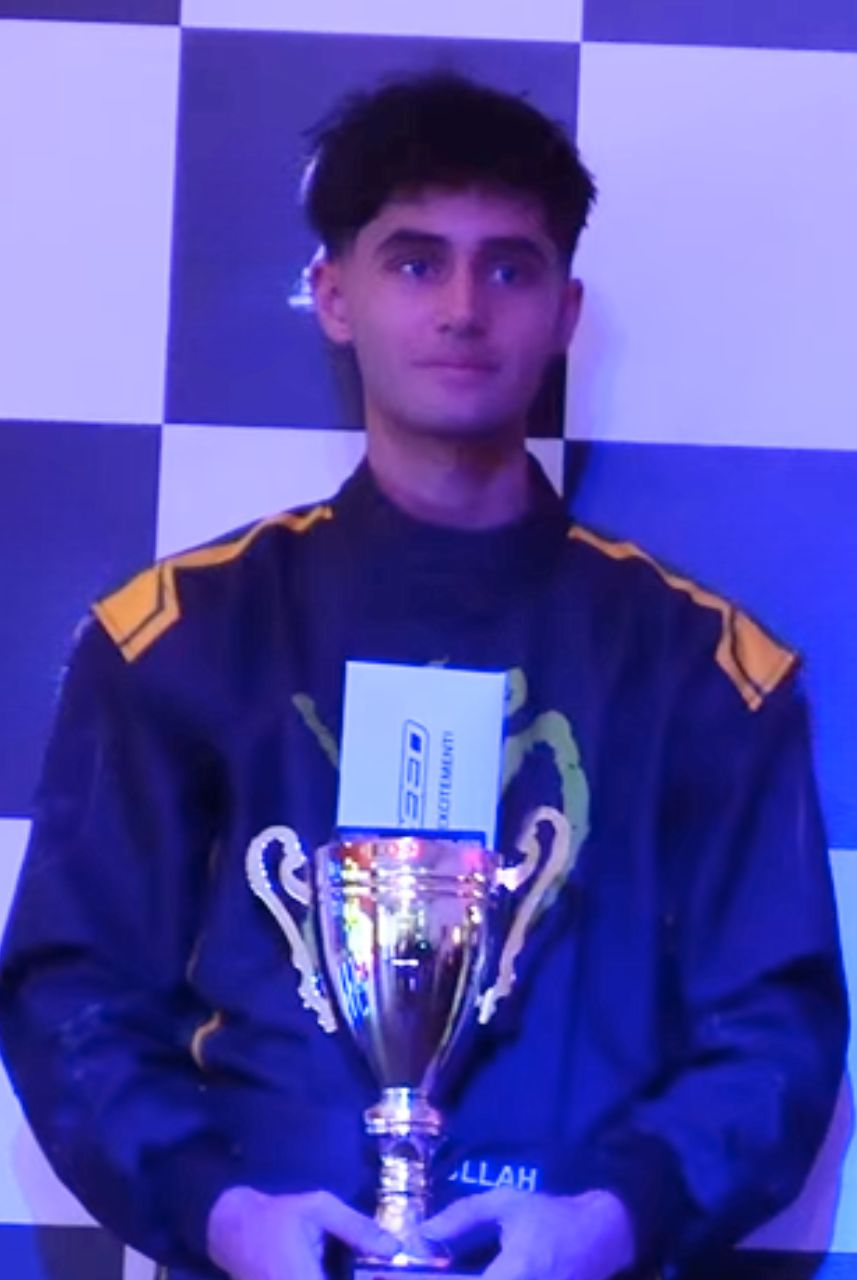 Go-kart racing driver holding a trophy during a podium ceremony at an indoor karting venue