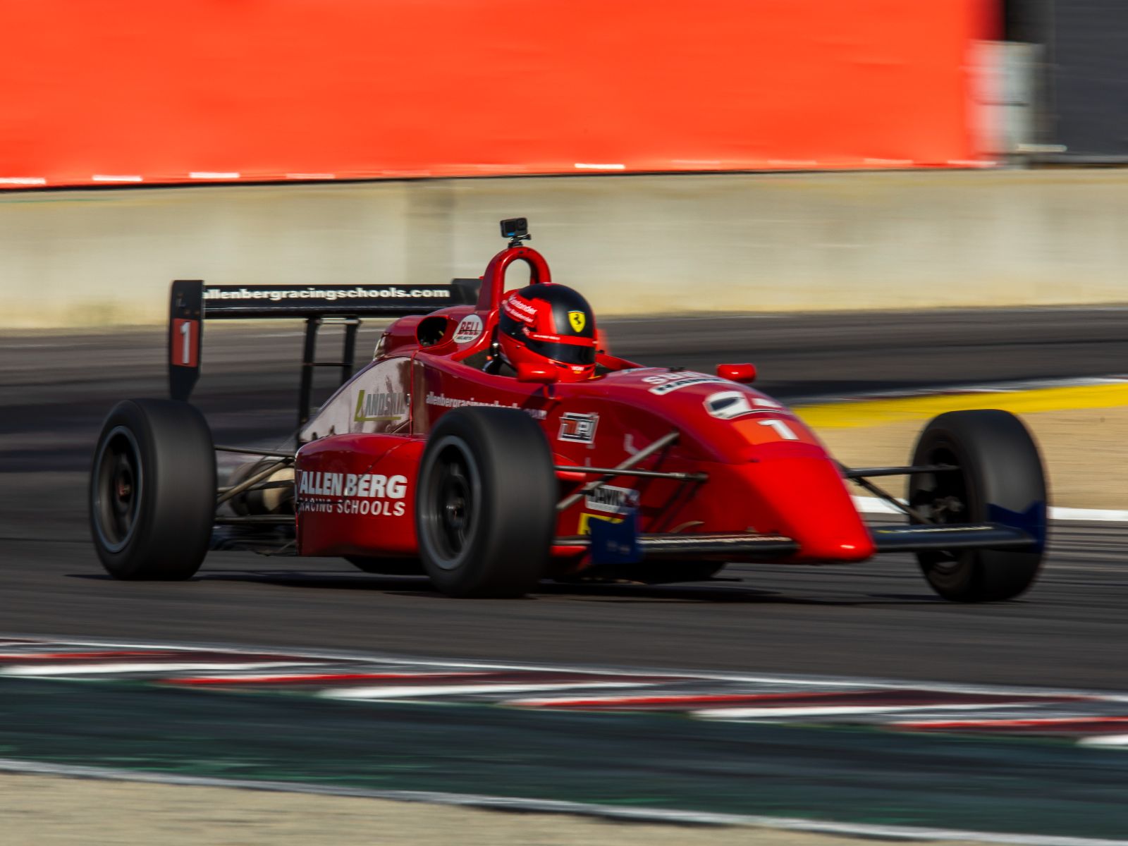 Red open-wheel formula race car accelerating through a corner on a professional racing circuit